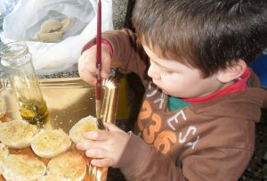 Criança a preparar torradas com azeite